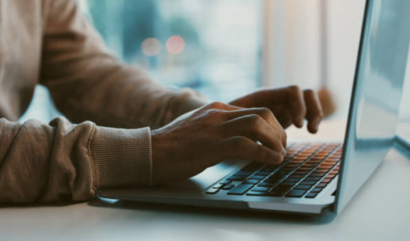 Hands typing on a laptop keyboard.