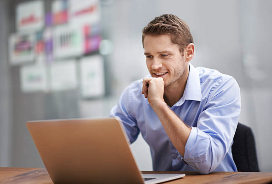 Young man in dress shirt working on laptop.